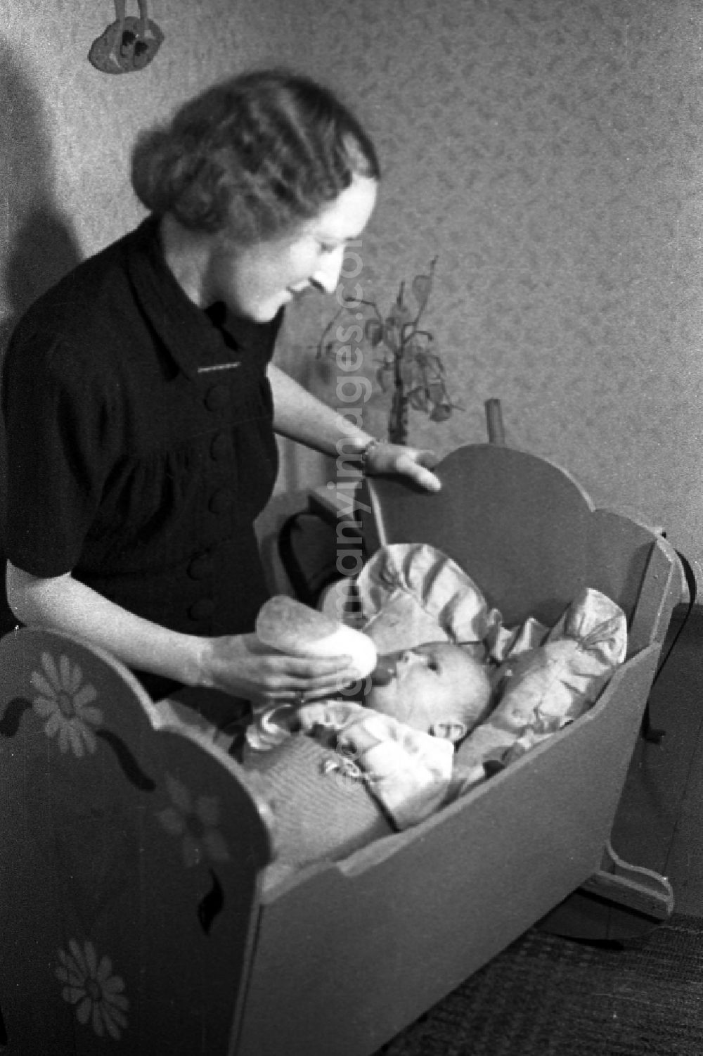 Merseburg: A mother gives to her baby in the cradle the teat bottle in Merseburg in the federal state Saxony-Anhalt in the area of the former GDR, German democratic republic