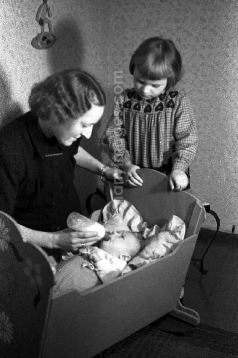 GDR image archive: Merseburg - A mother gives the teat bottle to her baby in the cradle and the big sister looks to in Merseburg in the federal state Saxony-Anhalt in the area of the former GDR, German democratic republic