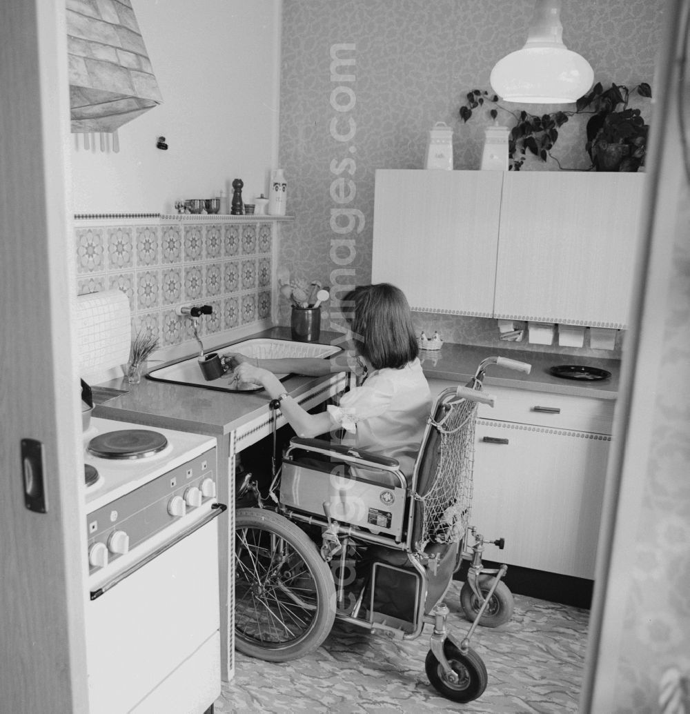 GDR image archive: Berlin - A wheelchair user, wash in her wheelchair in the kitchen, at her home in Berlin