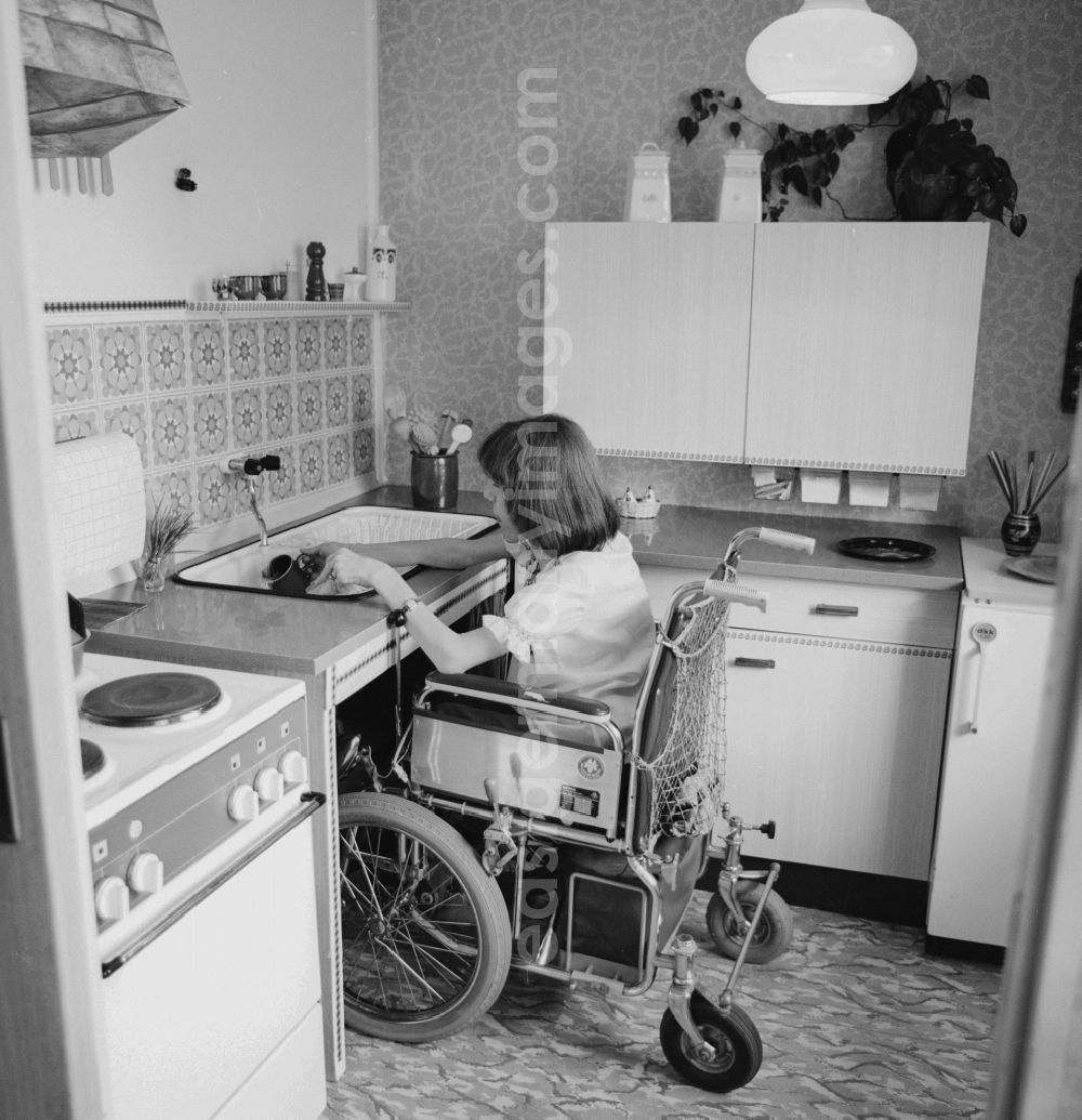 GDR photo archive: Berlin - A wheelchair user, wash in her wheelchair in the kitchen, at her home in Berlin