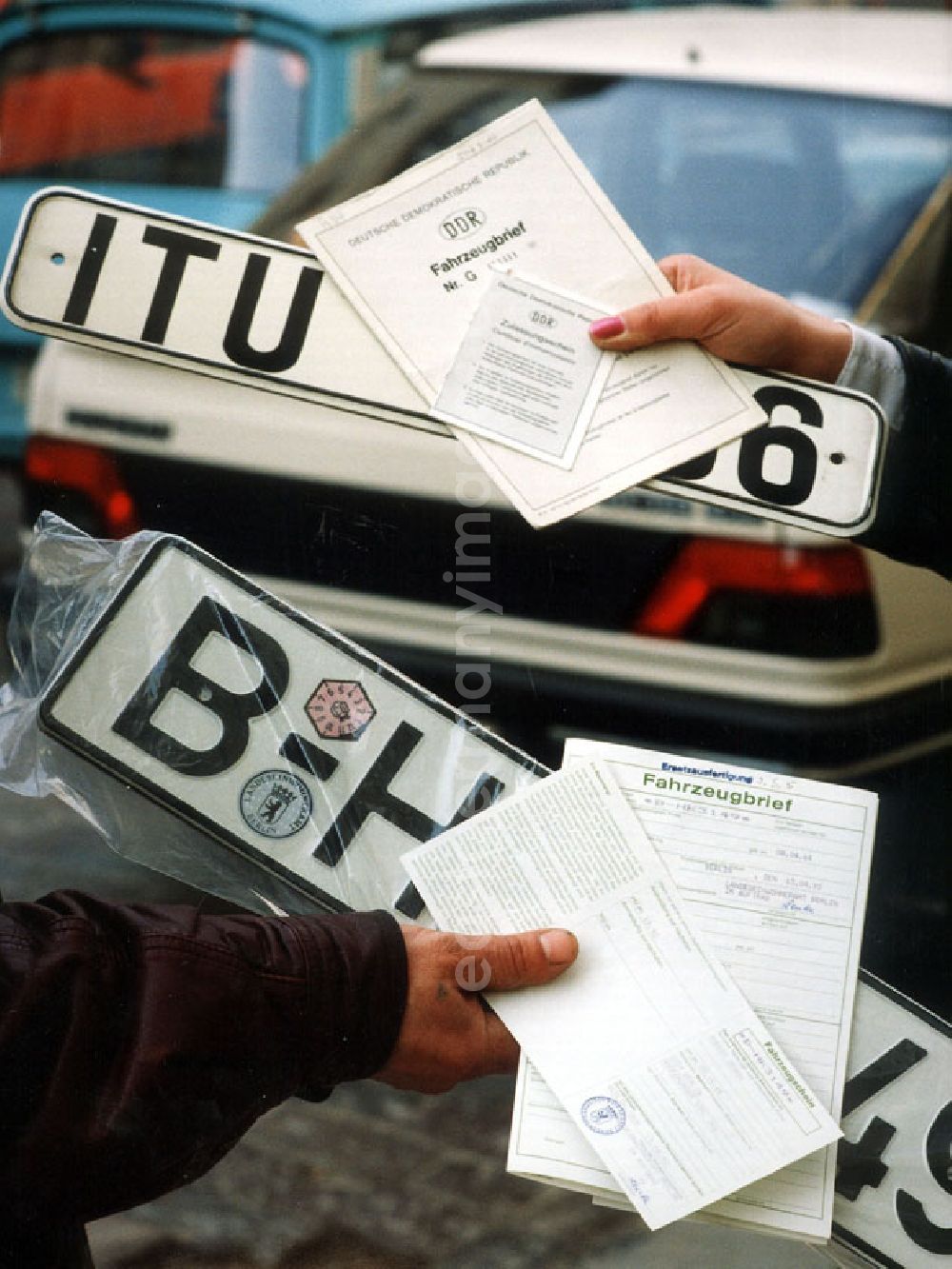 GDR image archive: Berlin - Umstellung der Autokennzeichen, alle Berliner Autos fahren bald nur mit dem Kennzeichen B. Hände halten DDR-Autokennzeichen, BRD-Autokennzeichen sowie jeweilige Autopapiere.