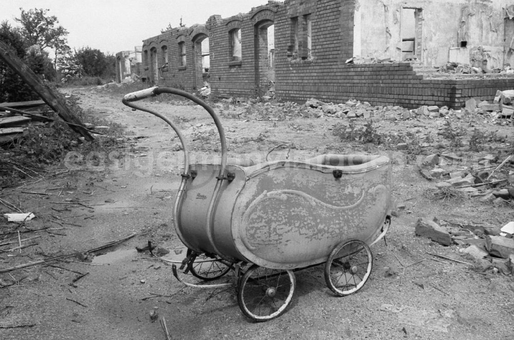 GDR picture archive: Groß-Lübbenau - An old basket stroller stands on the street in front of a ruin during demolition work on cleared and depopulated areas to expand the opencast mine for mining brown coal - ruins in Gross-Luebbenau Spreewald, Brandenburg on the territory of the former GDR, German Democratic Republic