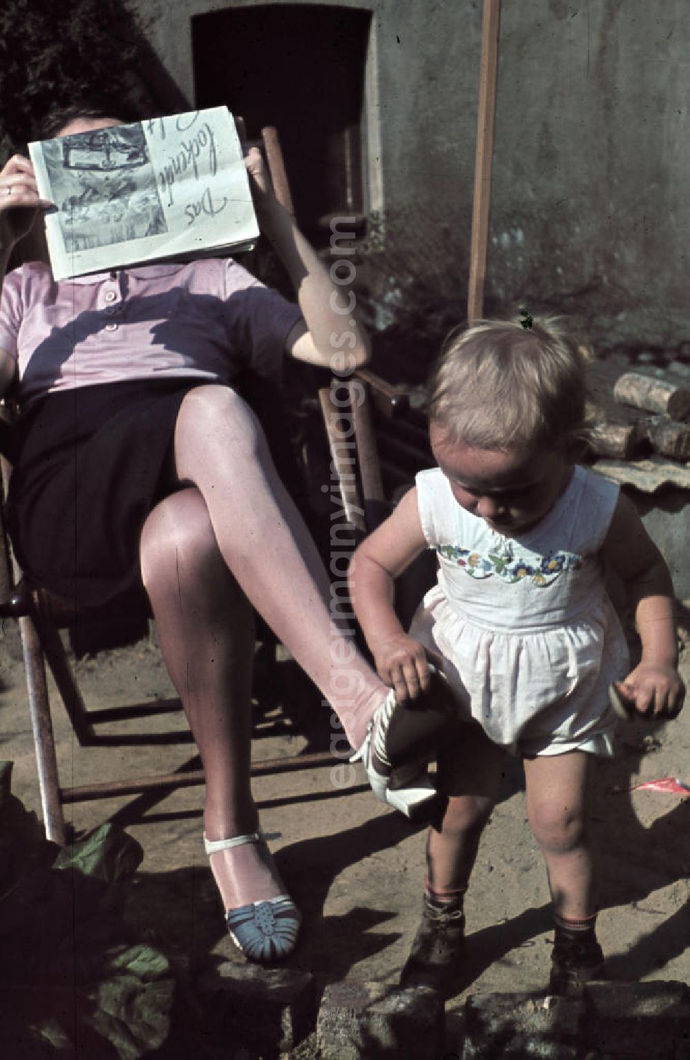 GDR image archive: Siegen - Kleinkind spielt im Garten, die Mutter sitzt im Liegestuhl und liest eine Zeitung. Plying infant in a garden. The mother is sitting in a deck chair and read a newspaper.