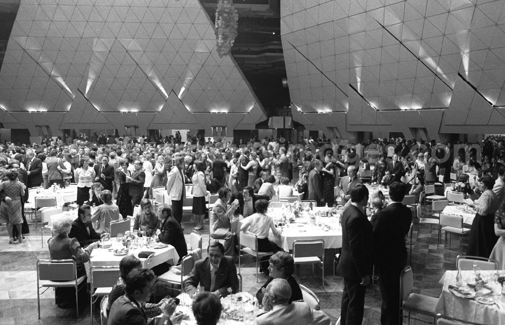 GDR photo archive: Berlin - Guests at tables and dancing in the Great Hall at the Palace of the Republic in the district Mitte in Berlin Eastberlin on the territory of the former GDR, German Democratic Republic. The Palace of the Republic in the GDR was one of the largest and most modern multi-purpose cultural buildings of its kind in Europe. In addition to catering facilities, the building housed a large multi-purpose hall and the parliament building of the People's Chamber of the GDR. The Great Hall could be converted into a banquet hall, concert hall or event hall with a maximum of 5,00