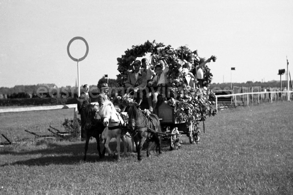 GDR photo archive: Dresden - Harvest wagon parade of horticultural and agricultural enterprises on the grounds of the Dresden-Seidnitz racecourse in Dresden in the state Saxony on the territory of the former GDR, German Democratic Republic. Pioneers wear pioneer scarfs on the horse-drawn carriage and wave