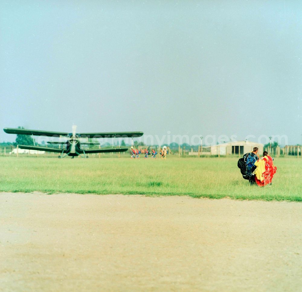 GDR photo archive: Leipzig - An aircraft of type Antonov AN-2 and paratroopers on the GST airfield in Leipzig-Mockau in Saxony in the area of the former GDR, German Democratic Republic