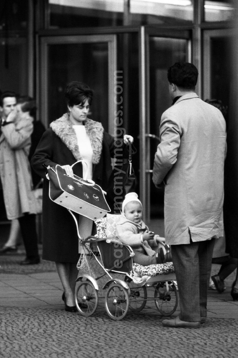 GDR photo archive: Berlin - Mother and father stroll with their child in a stroller in East Berlin in the territory of the former GDR, German Democratic Republic