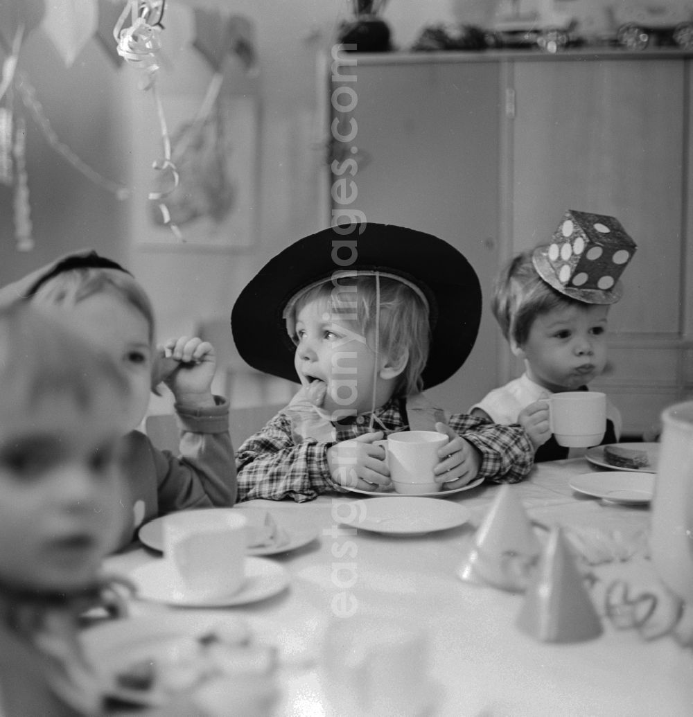 GDR photo archive: Berlin - Carnival in kindergarten in Berlin. The clad children sit at the table decorated Vesper