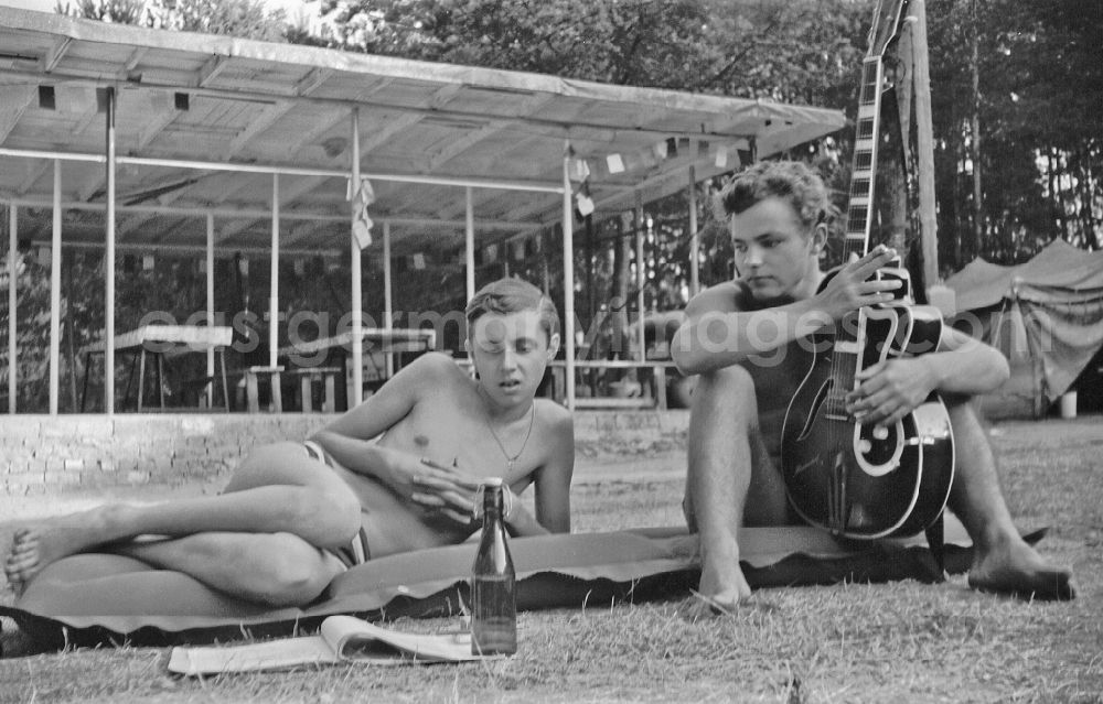 GDR photo archive: Stechlin - Summer camp operation with pupils and teenagers with guitar on an air mattress in Menz, Brandenburg on the territory of the former GDR, German Democratic Republic