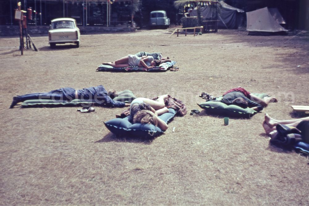 Menz: Summer camp operation with pupils and teenagers on air mattresses in front of tents on street Fuerstenberger Strasse in Menz, Brandenburg on the territory of the former GDR, German Democratic Republic