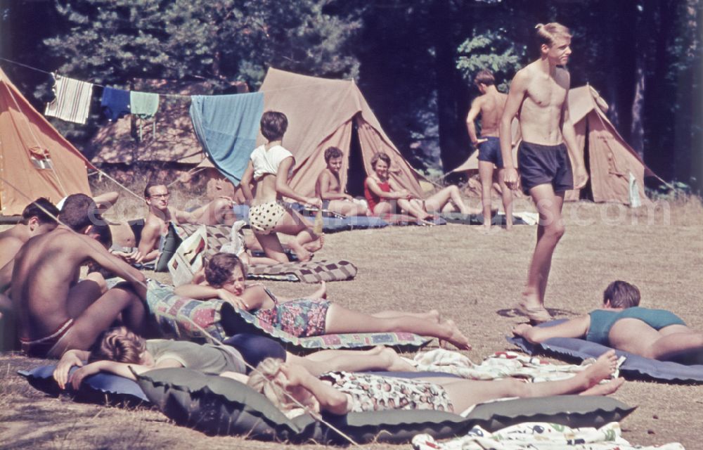 GDR image archive: Menz - Summer camp operation with pupils and teenagers on air mattresses in front of tents on street Fuerstenberger Strasse in Menz, Brandenburg on the territory of the former GDR, German Democratic Republic