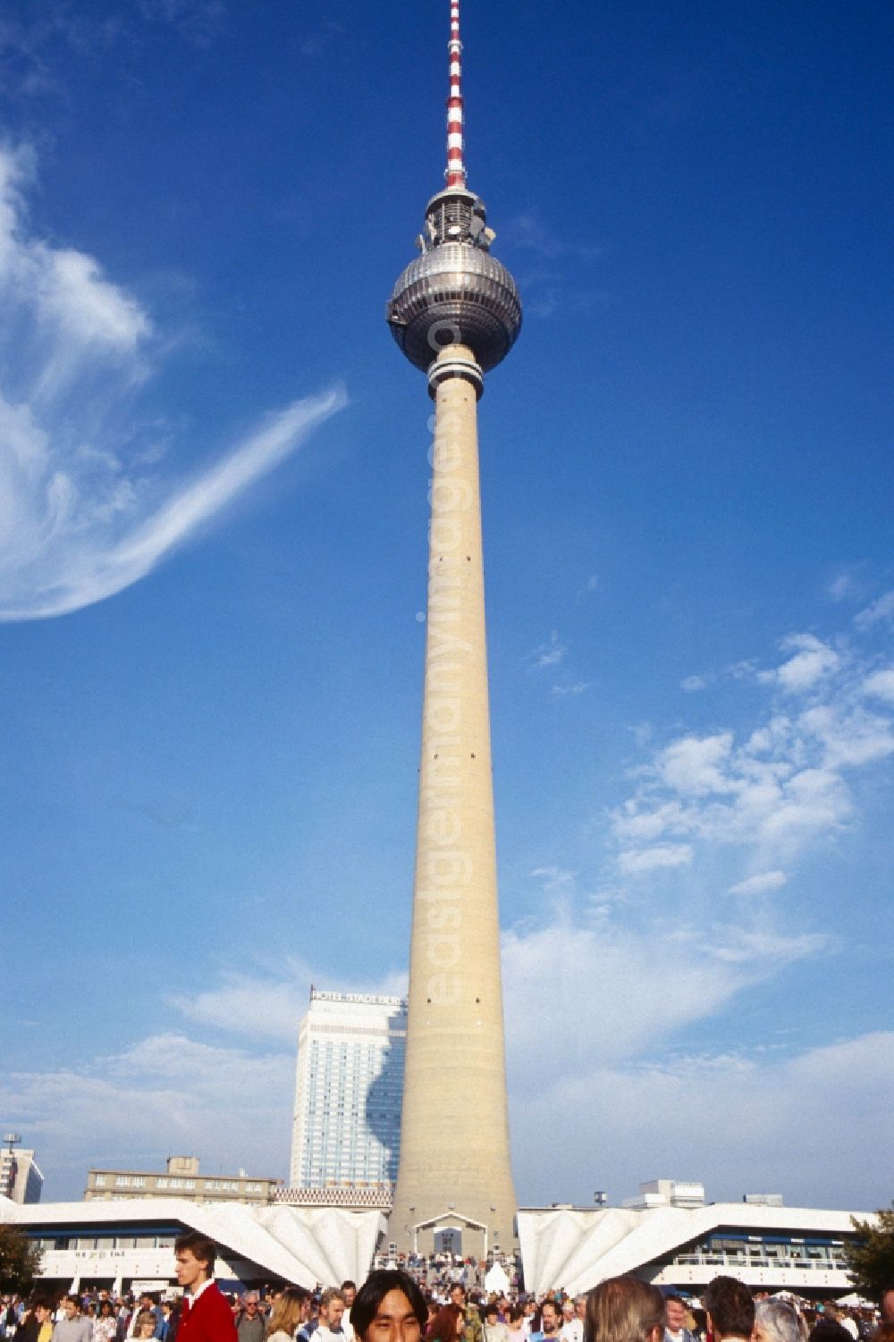 GDR photo archive: Berlin - Mitte - View of the TV Tower with the Hotel Stadt Berlin in the background in Berlin - Mitte. The Berlin TV Tower is the tallest building in Germany. As a politically simplistic ahmtes symbol of the GDR, the distinctive and influential city building has undergone a transition to the citywide icon in reunited Berlin