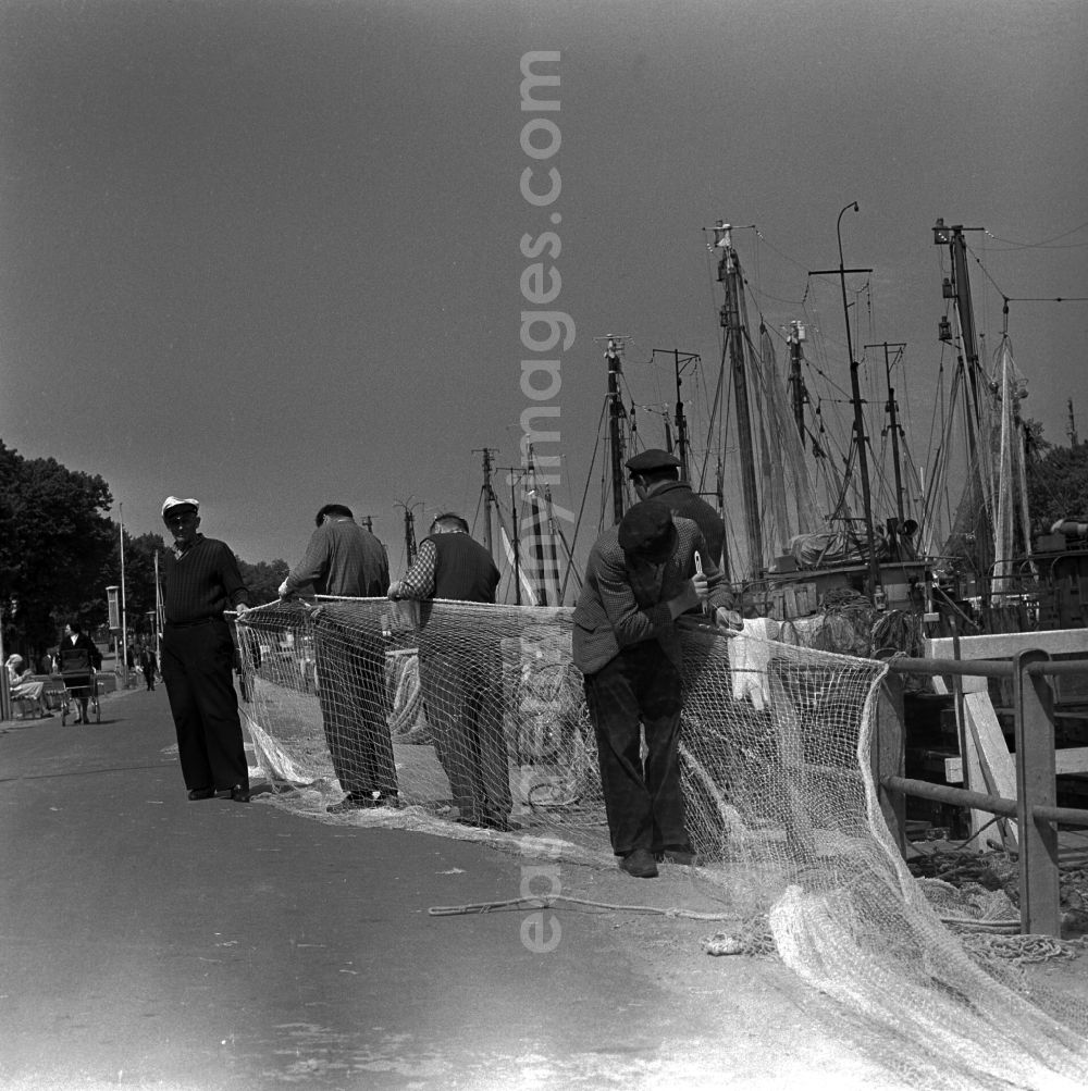 GDR image archive: Warnemünde - Fishermen make a fishing net with a net needle in Warnemunde