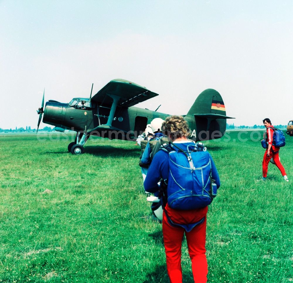 GDR picture archive: Leipzig - An aircraft of type Antonov An-2 and paratroopers on the GST airfield in Leipzig-Mockau in Saxony in the area of the former GDR, German Democratic Republic