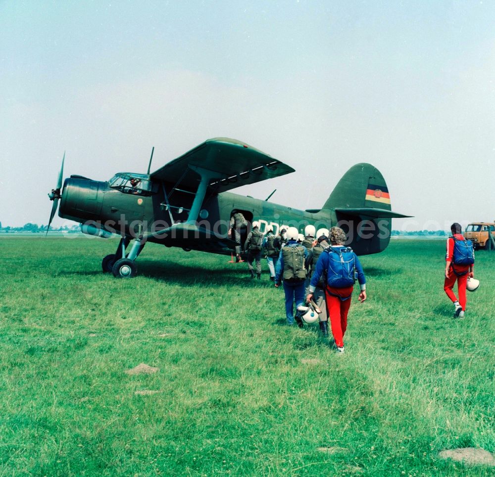 Leipzig: An aircraft of type Antonov An-2 and paratroopers on the GST airfield in Leipzig-Mockau in Saxony in the area of the former GDR, German Democratic Republic