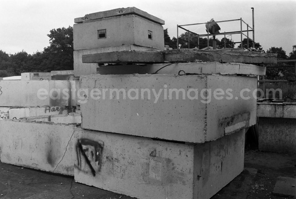 GDR picture archive: Berlin - Fragments of the decaying and dismantled watchtower concrete elements of the border fortifications and wall as well as security structures in the former blocking strip of the state border at a camp of the border troops in the district of Steinstuecken in Berlin on the territory of the former GDR, German Democratic Republic