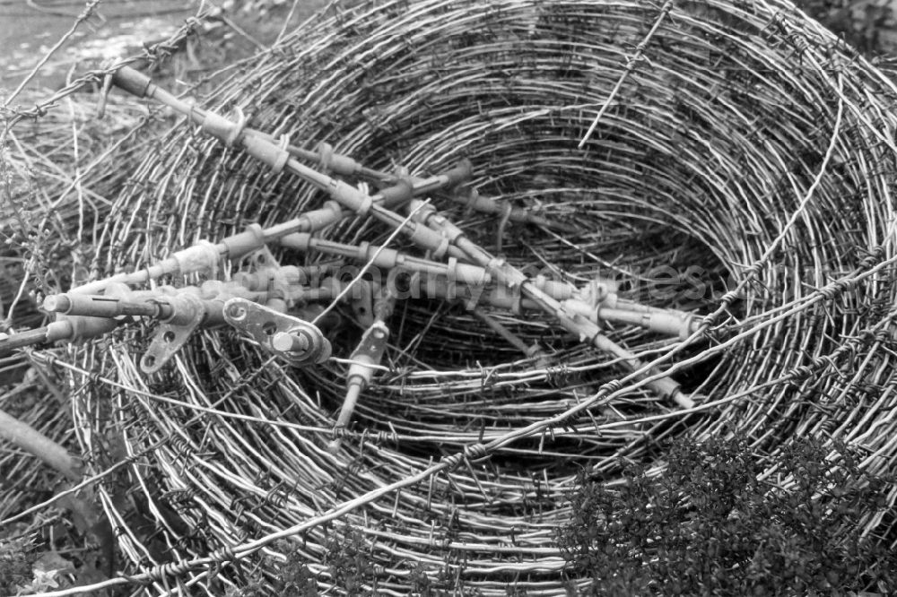 GDR photo archive: Berlin - Barbed wire rolls of the barriers of the border fortifications and wall as well as security structures in the former blocking strip of the state border at a camp of the border troops in the Steinstuecken district in Berlin on the territory of the former GDR, German Democratic Republic
