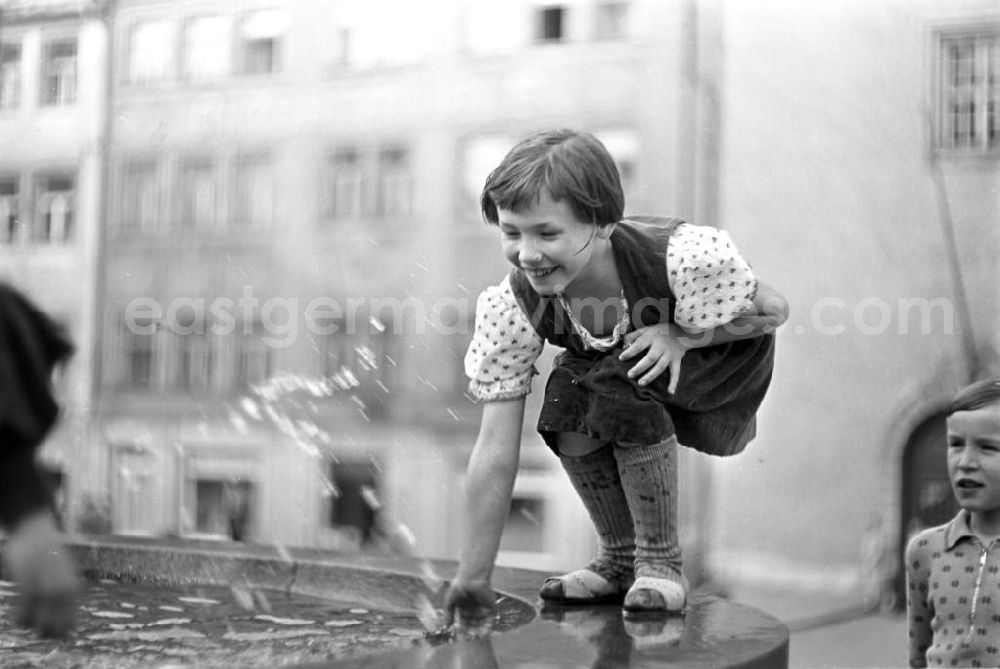 Freiberg: Ein Mädchen plantscht lachend mit der Hand in einem Springbrunnen in Freiberg.