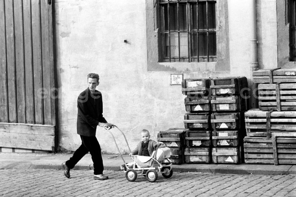 GDR photo archive: Freiberg - Ein Mann schiebt einen Kinderwagen, in dem ein Kleinkind sitzt, über eine Straße in Freiberg.