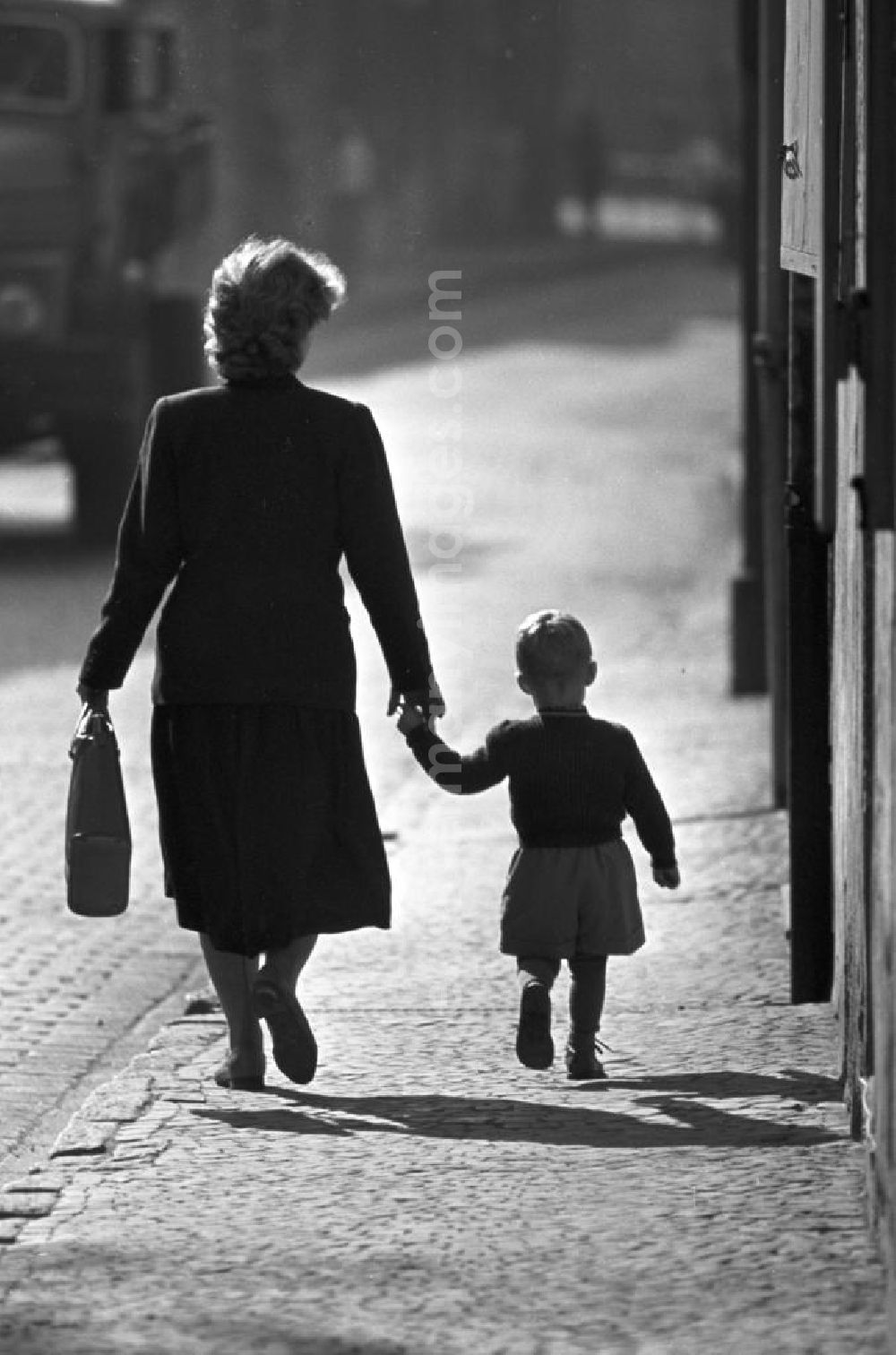 GDR picture archive: Freyburg - Hand in Hand läuft eine Frau mit ihrem kleinen Jungen durch eine Straße in Freyburg an der Unstrut.