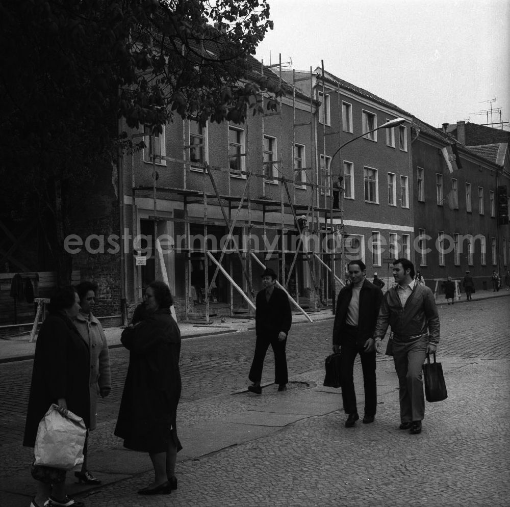 GDR image archive: Fürstenwalde - Alltagsszene / Stadtansicht. Eine Gruppe Frauen im Gespräch, Fußgänger gehen vorbei und Bauarbeiter demontieren ein Baugerüst.