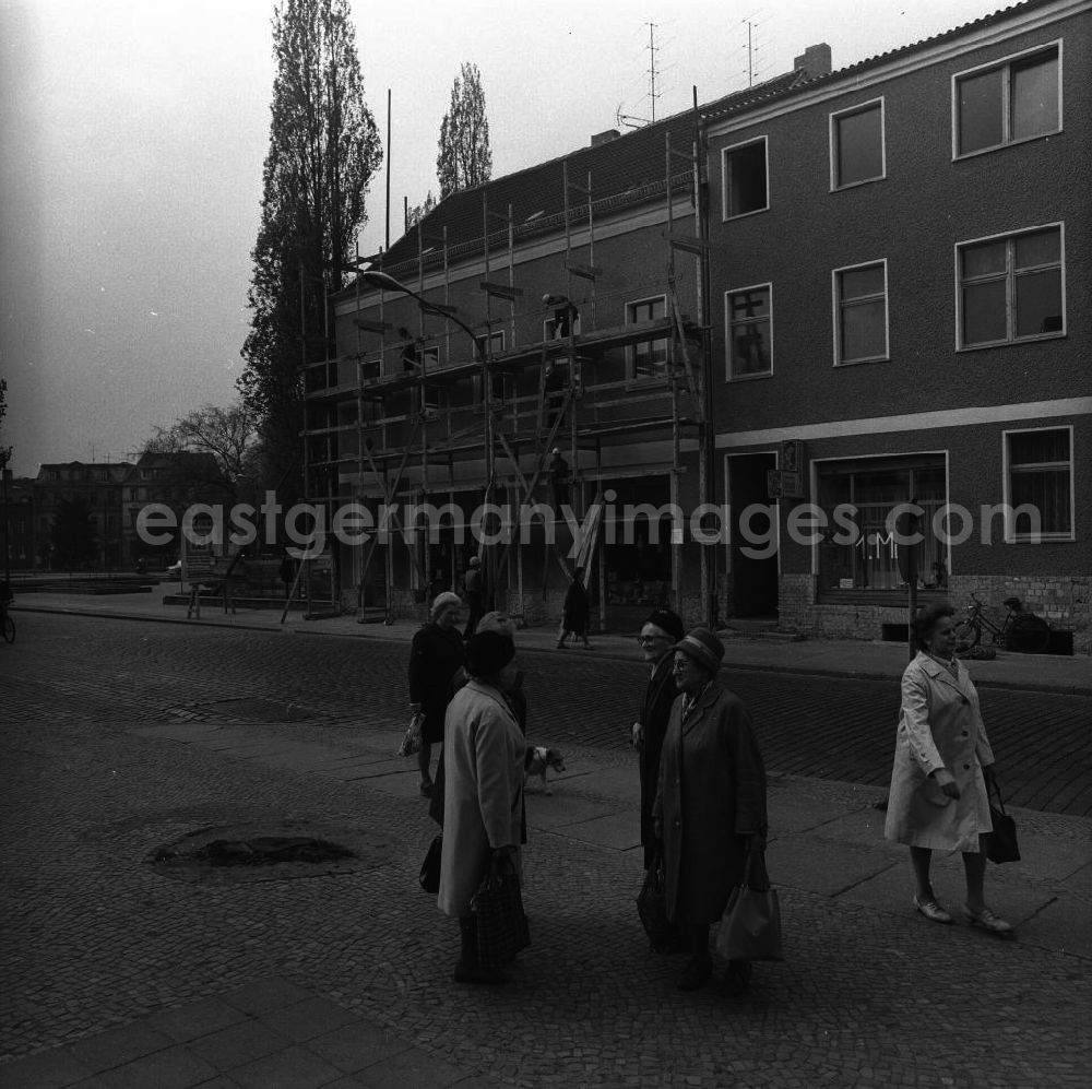 GDR photo archive: Fürstenwalde - Gruppe älterer Damen führt eine Unterhaltung auf dem Bürgersteig. Passanten nähern sich der Gruppe, gehen an ihr vorbei und überqueren die Straße. Im Hintergrund bauen Arbeiter ein Gerüst ab.