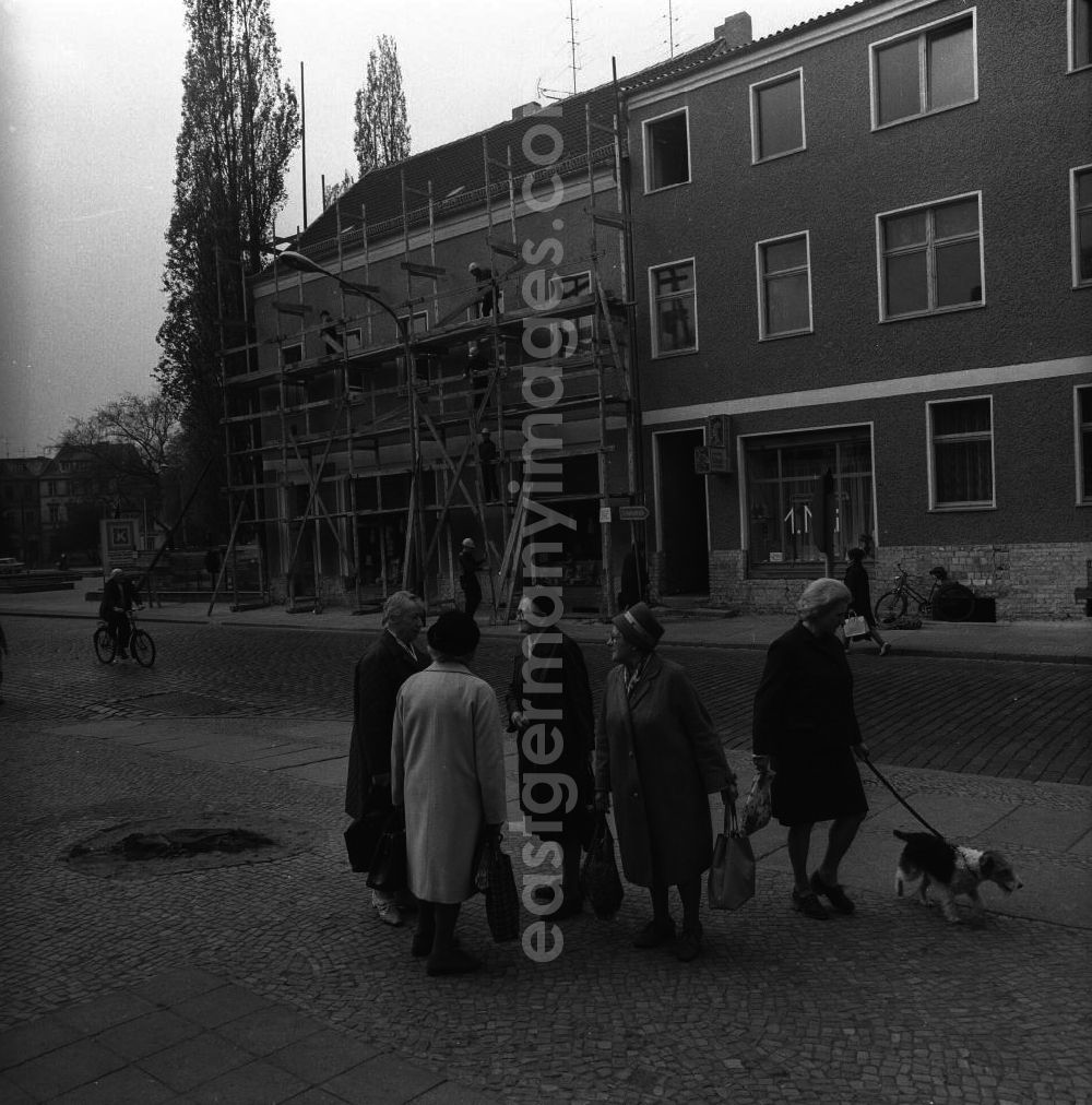 Fürstenwalde: Gruppe älterer Damen führt eine Unterhaltung auf dem Bürgersteig. Passanten nähern sich der Gruppe, gehen an ihr vorbei und überqueren die Straße. Im Hintergrund bauen Arbeiter ein Gerüst ab.