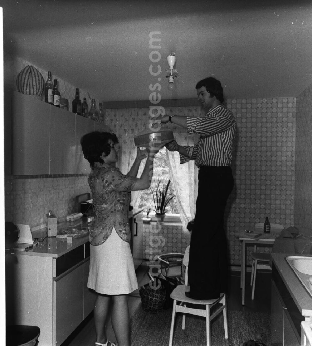 GDR photo archive: Fürstenwalde - Küche in der Neubauwohnung einer jungen Familie im Stil der siebziger Jahre. Ein junges Paar wechselt die Glühbirne der Küchen-Leuchte.