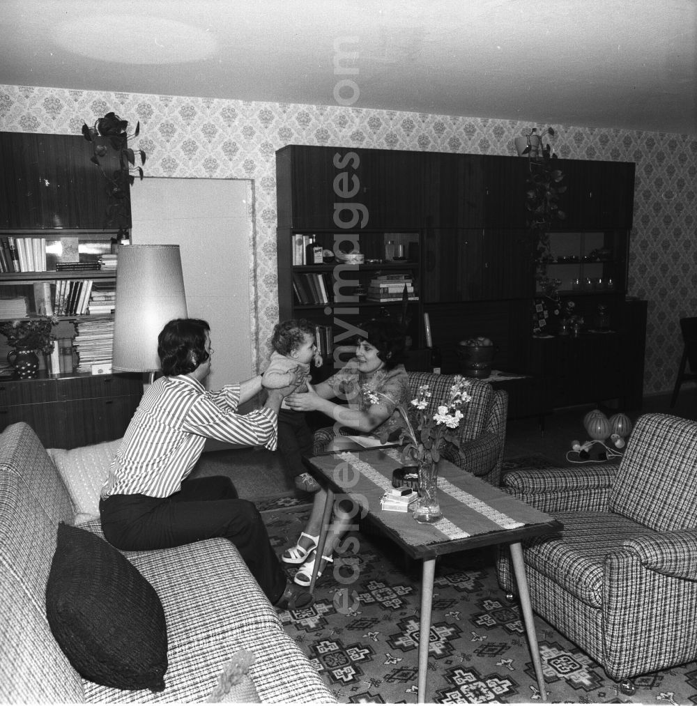 GDR photo archive: Fürstenwalde - In der Wohnung einer jungen Familie / im Wohnzimmer. Die Wohnung ist im Stil der siebziger Jahre eingerichtet. Im Hintergrund Schrankwand Typ Hellerau. Das Paar sitzt mit seinem Kind / Baby auf dem Sofa.