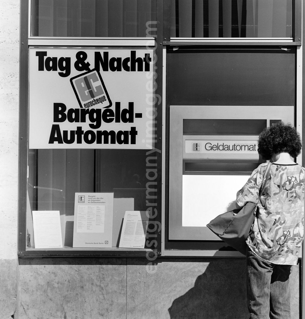 GDR image archive: Berlin - A woman collects money at the Deutsche Bank Berlin cash dispenser in Berlin