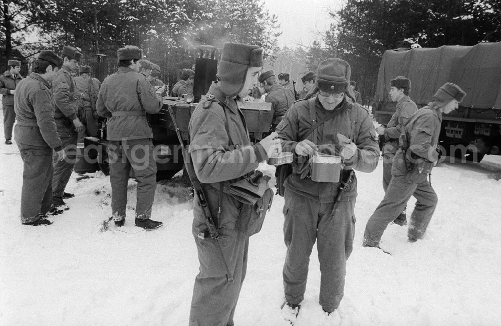 GDR picture archive: Königs Wusterhausen - Communal catering during a manoeuvre, in winter from the goulash cannon, the 2nd news regiment of the NVA in Wernsdorf in Koenigs Wusterhausen in the federal state Brandenburg in the area of the former GDR, German democratic republic