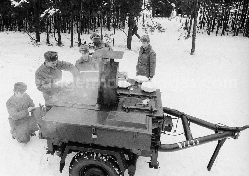 GDR image archive: Königs Wusterhausen - Communal catering during a manoeuvre, in winter from the goulash cannon, the 2nd news regiment of the NVA in Wernsdorf in Koenigs Wusterhausen in the federal state Brandenburg in the area of the former GDR, German democratic republic