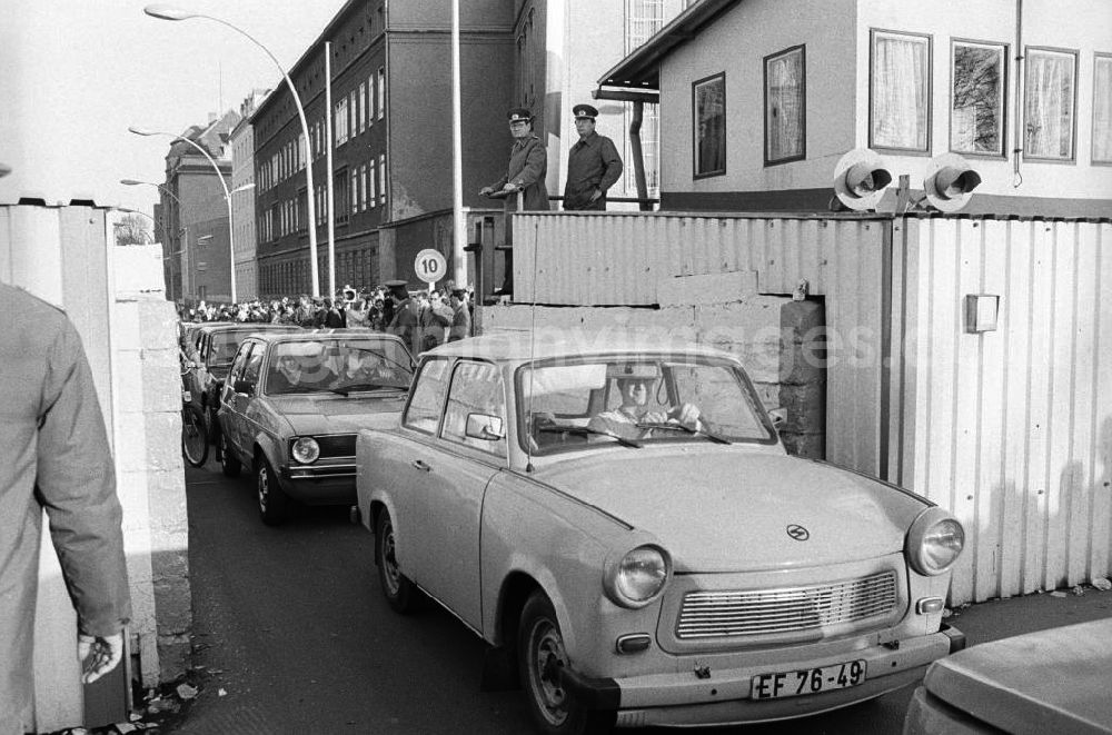 Berlin: Mauerfall / Grenzübergang Invalidenstraße, Bürger fahren mit Auto vom Typ Trabant durch Tor am Grenzübergang. Polizisten / Volkspolizisten stehen auf Erhöhung im Hintergrund und schauen zu.
