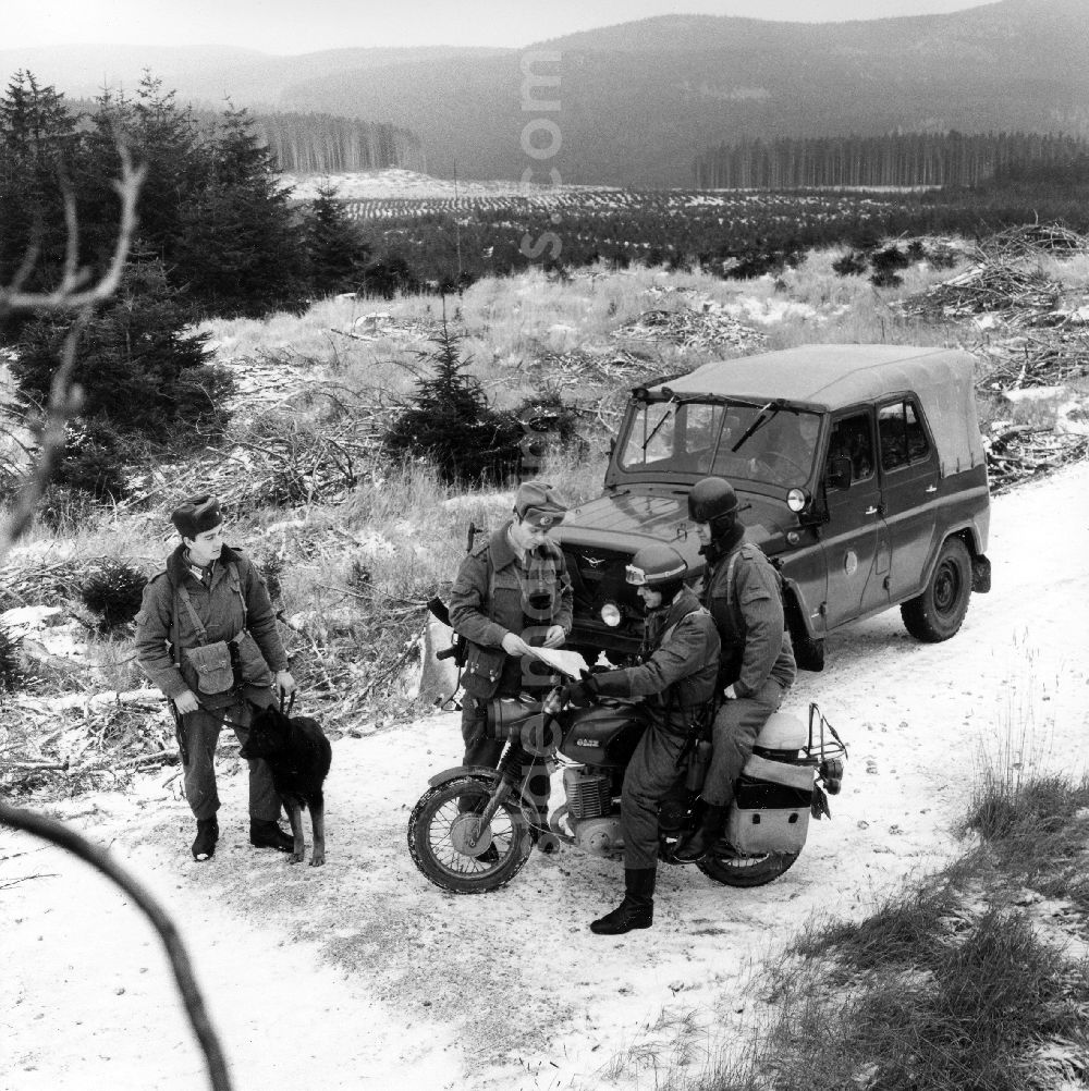 GDR photo archive: Abbenrode - Border Patrol in snow in the winter with dog, car and motorcycle near Abbenrode in today's federal state of Saxony-Anhalt. The border guards are equipped with AK-47 machine guns