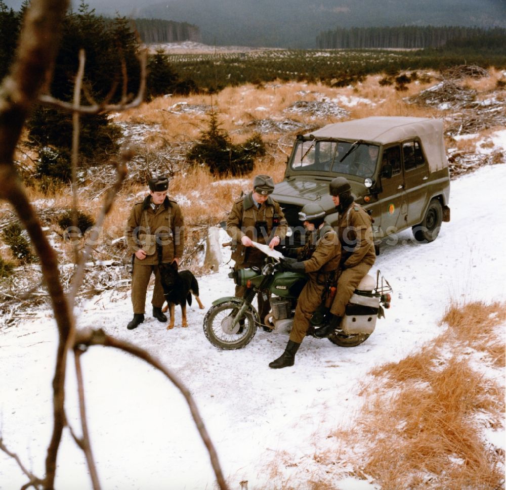 GDR picture archive: Abbenrode - Border Patrol in snow in the winter with dog, car and motorcycle near Abbenrode in today's federal state of Saxony-Anhalt. The border guards are equipped with AK-47 machine guns