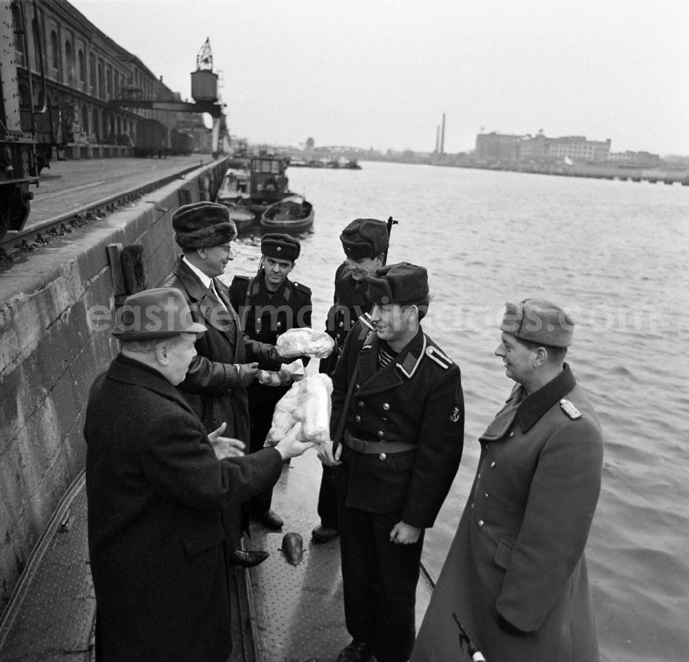 GDR image archive: Berlin - Soldiers in the uniform of the border troops - sailors of the boat company of the border regiment - 36 Helmut Poppe at the presentation of New Year's gifts by the 1st Secretary of the SED - district leadership Gerhard Kowalschik on the banks of the Spree of the Berlin Osthafen in the district of Friedrichshain in Berlin East Berlin in the area of former GDR, German Democratic Republic