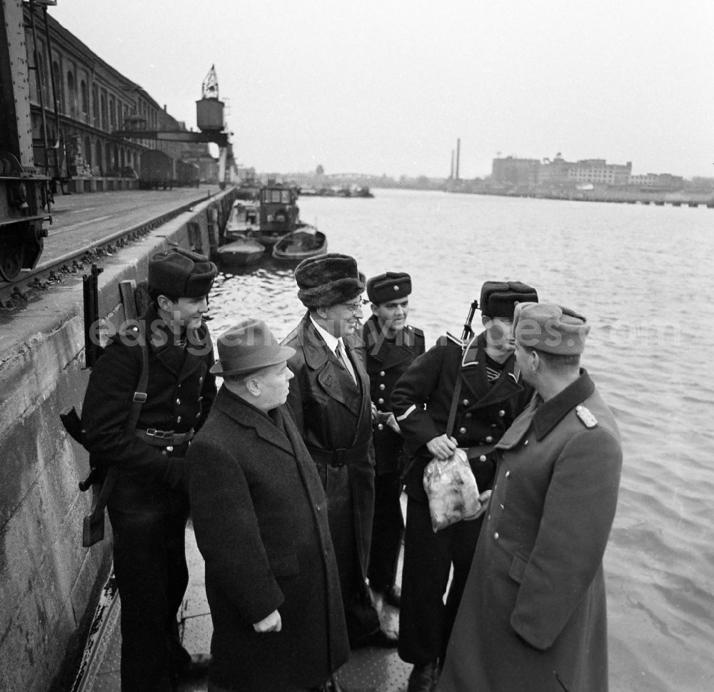 GDR photo archive: Berlin - Soldiers in the uniform of the border troops - sailors of the boat company of the border regiment - 36 Helmut Poppe at the presentation of New Year's gifts by the 1st Secretary of the SED - district leadership Gerhard Kowalschik on the banks of the Spree of the Berlin Osthafen in the district of Friedrichshain in Berlin East Berlin in the area of former GDR, German Democratic Republic