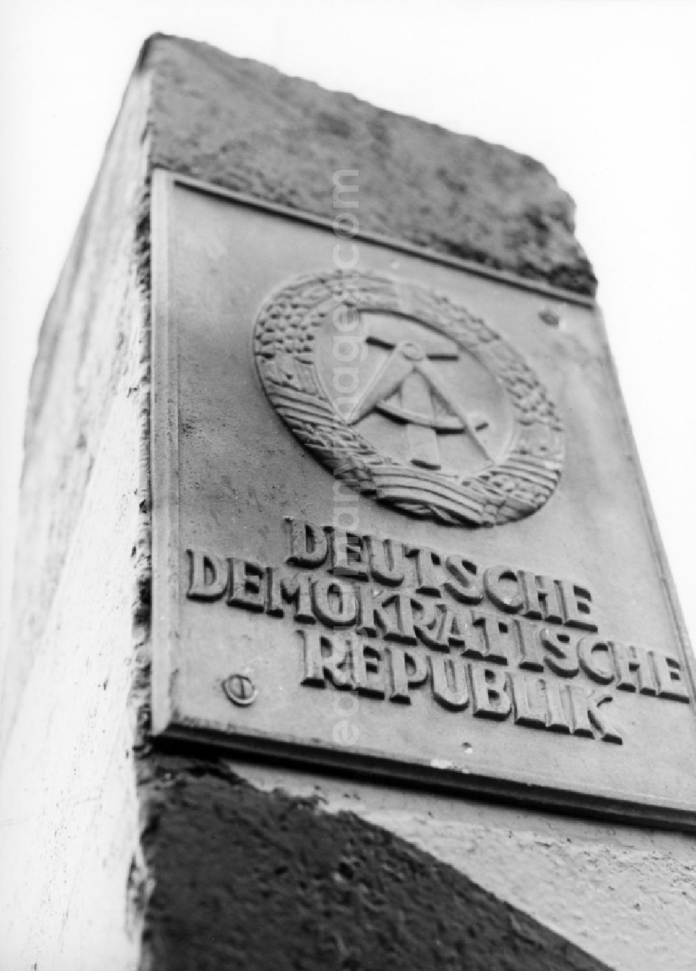 GDR picture archive: Abbenrode - Landmark with gray cast iron board of the GDR at the border to West Germany near Abbenrode in today's state of Saxony-Anhalt. The photo shows a concrete column with gray cast iron board, which includes the state emblem of the GDR hammer, circle and wreath of honor and the inscription German Democratic Republic 
