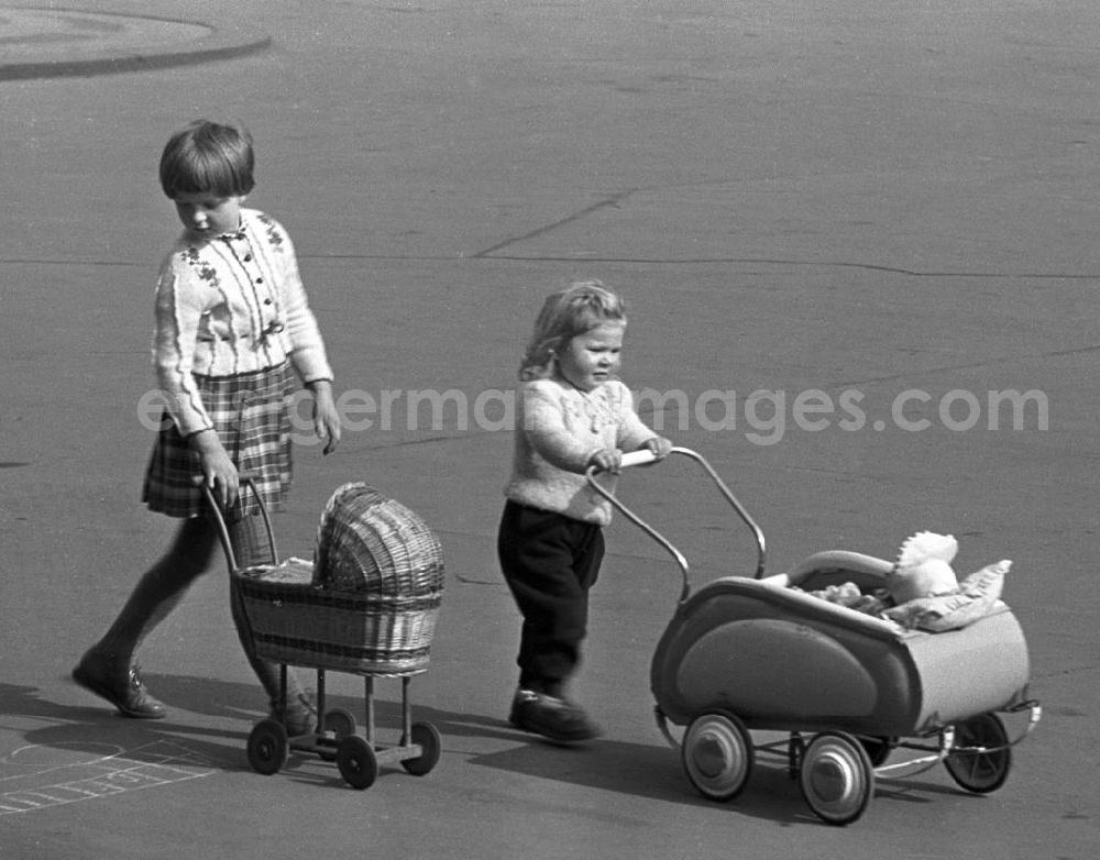 Leipzig: Stolz schiebt das kleine Mädchen den Puppenwagen der großen Schwester vor sich her, die ihren Wagen für kurze Zeit getauscht hat.