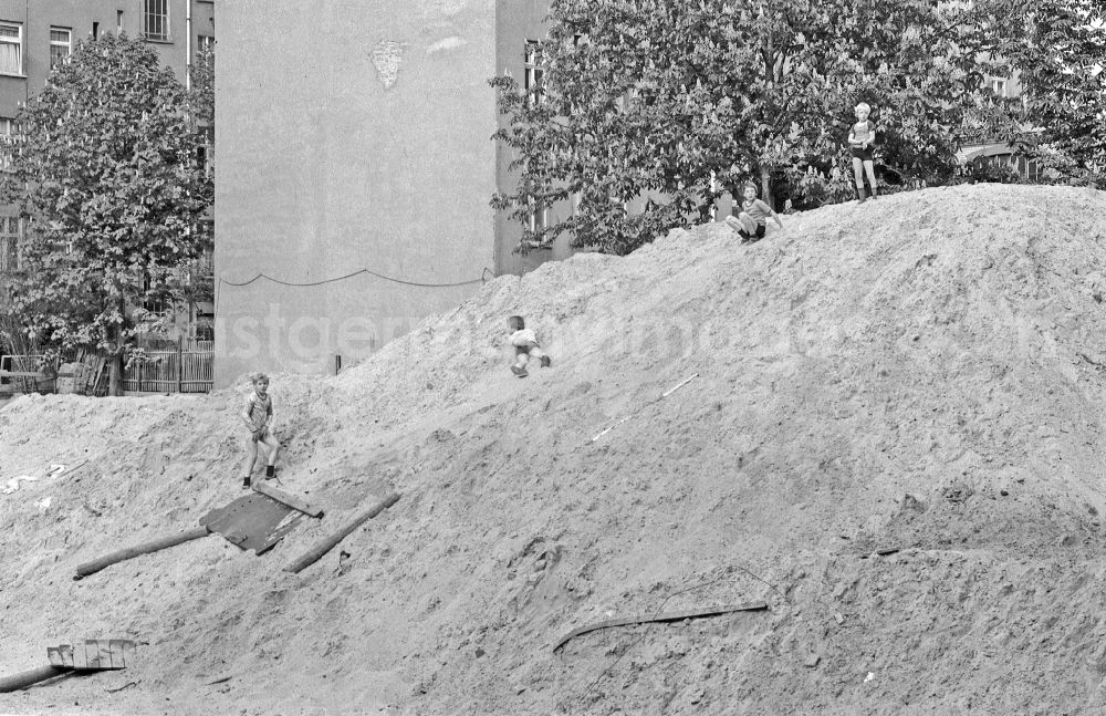 Berlin: Fun and games for children and teenagers on a heap of sand on a construction site on street Corinthstrasse in Berlin Eastberlin on the territory of the former GDR, German Democratic Republic