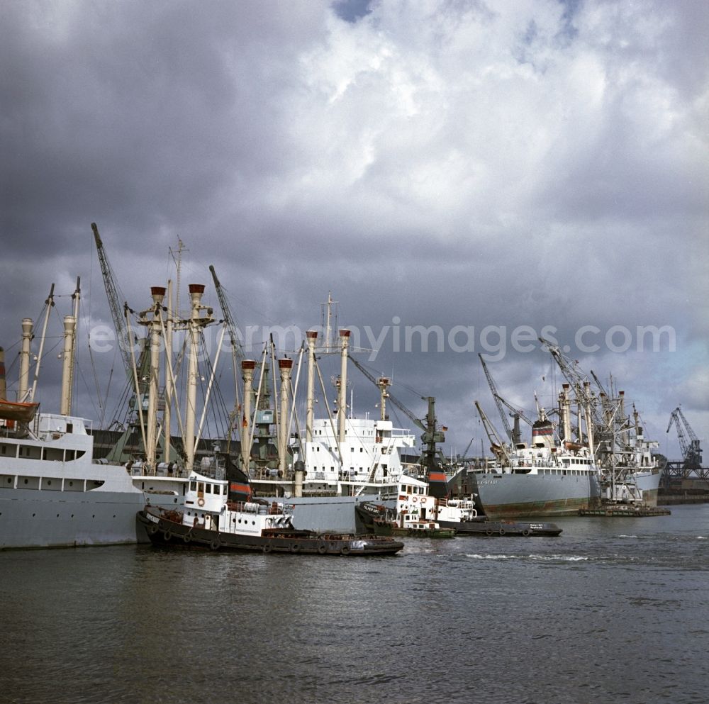 GDR photo archive: Rostock - Merchant ships in the seaport of Rostock in Mecklenburg - Western Pomerania. Here during loading at the port. By the division of Germany resulted in the need to build on the Baltic coast of East Germany a seaport