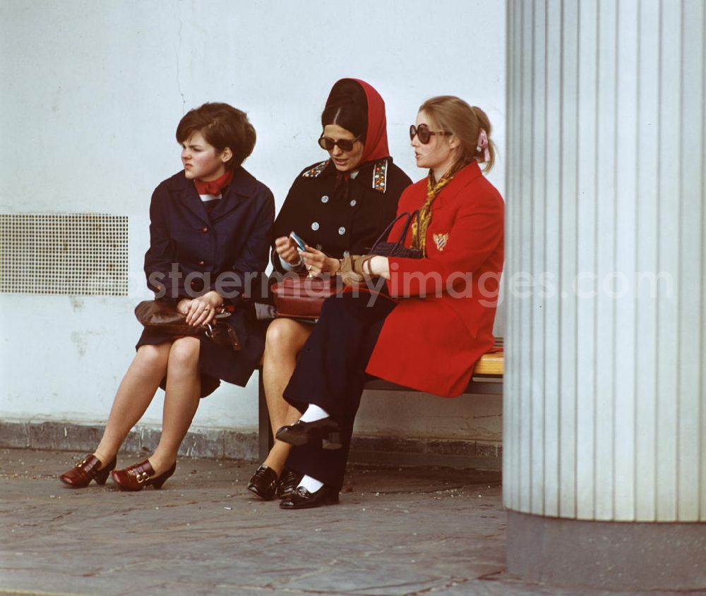 GDR picture archive: Berlin - Drei schick gekleidete Frauen sitzen auf einer Bank im Säulengang am Haus des Lehrers am Alexanderplatz in Berlin-Mitte.