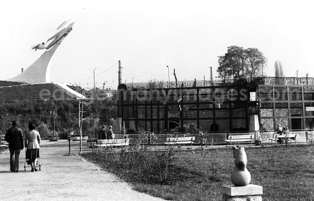 GDR picture archive: Merseburg - Besucher gehen durch den Heimattierpark Südpark. Im Hintergrund ist ein sowetisches Jagdflugzeug, Mikojan-Gurewitsch MiG 15, als Fliegerdenkmal aufgestellt.