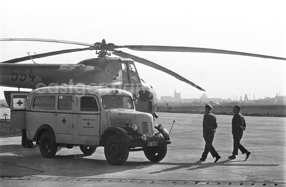 GDR image archive: Leipzig - Im Vordergrund zu sehen ist ein ein Krankenwagen vom Typ Robur. Hinter dem Krankenwagen vom Roten Kreuz steht ein Hubschrauber des Typs Mil Mi-4. Die Mil Mi-4 ist ein sowjetischer / russischer Hubschrauber / Helikopter, der von der NVA genutzt wurde. Neben den Fahrzeugen ein Mann in zivil und ein Militär. Bestmögliche Qualität nach Vorlage!