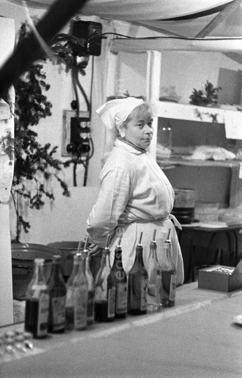 GDR picture archive: Leipzig - Eine Frau steht auf dem Leipziger Weihnachtsmarkt hinter der Theke einer Imbißbude und wartet auf Kundschaft.