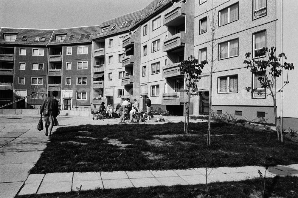 GDR image archive: Erfurt - Blick in den Innenhof eines Neubaugebietes mit Plattenbauten im Hintergrund. Eltern mit ihren Kindern spielen zusammen auf dem Spielplatz.