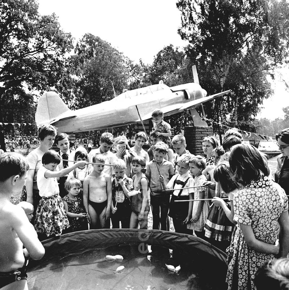 Berlin: Kinder vor Planschbecken / Pool Angeln Plastik-Fische am Internationaler Kindertag. Im Hintergrund Ausstellungs-Flugzeug einer Jak-18A (zweisitziges Trainingsflugzeug Jakowlew Jak-18).
