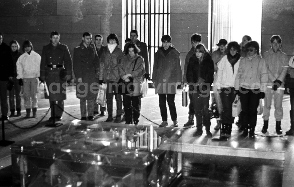 GDR image archive: Berlin - Joint visit by soldiers and army members of the NVA fighter squadron Heinrich Rau and young people from a civilian mentor brigade in front of the Eternal Flame in the national memorial against the victims of war and fascism in Schinkel's Neue Wache on the boulevard Unter den Linden in the Mitte district in Berlin East Berlin on the territory of the former GDR, German Democratic Republic