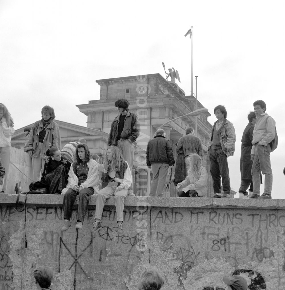 Berlin: Young people and tourists sit on the Berlin Wall at the Brandenburg Gate in Berlin