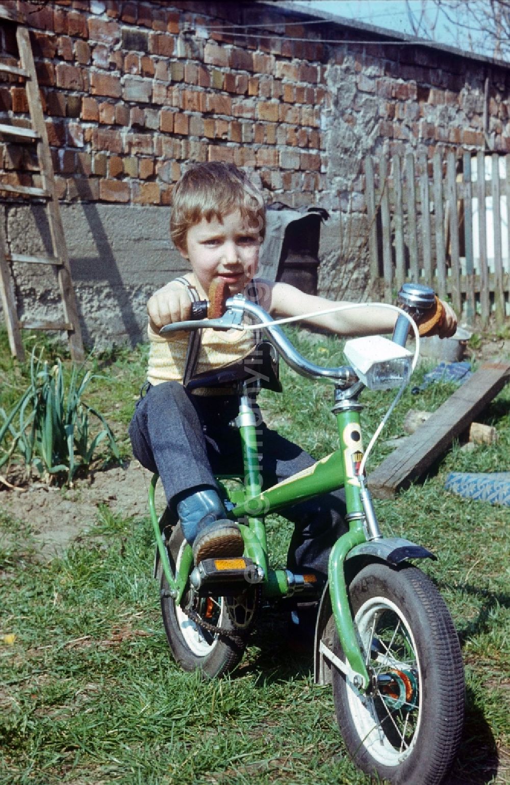 GDR picture archive: Neustrelitz - Boy on a green flash children's bicycle in Neustrelitz in the federal state Mecklenburg-West Pomerania in the area of the former GDR, German democratic republic